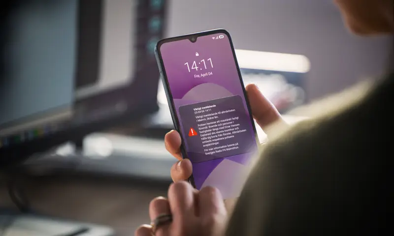 En person som håller en mobiltelefon i handen.