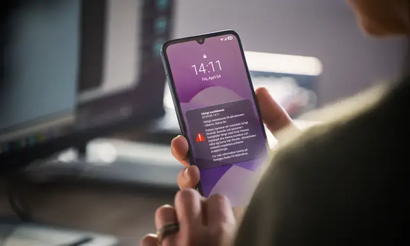 En person som håller en mobiltelefon i handen.